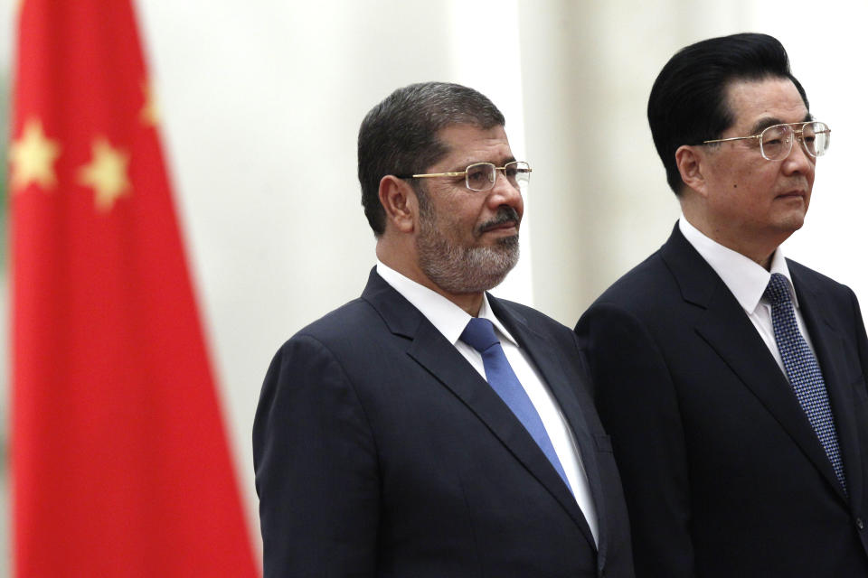 Egyptian President Mohammed Morsi, center, and Chinese President Hu Jintao stand near a Chinese national flag during a welcome ceremony held at the Great Hall of the People in Beijing Tuesday, Aug. 28, 2012. China is hosting Egypt's newly elected president despite its uneasiness with the Arab Spring revolution that helped bring him to power, while the new leader seeks to shore up his country's flagging economy. (AP Photo/Ng Han Guan)