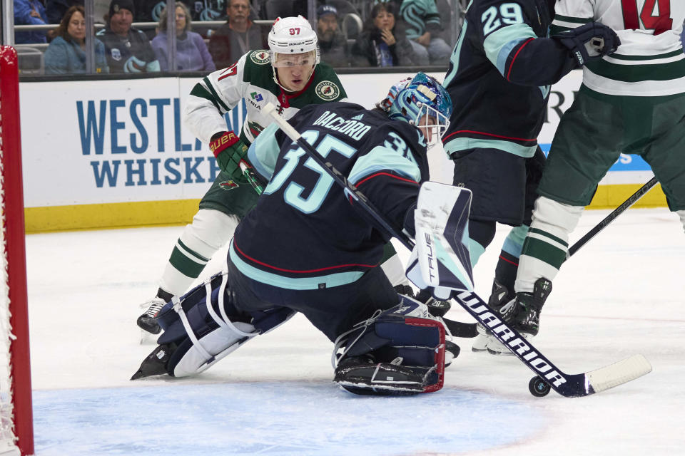 Seattle Kraken goaltender Joey Daccord (35) knocks the puck away with Minnesota Wild left wing Kirill Kaprizov (97) skating nearby during the second period of an NHL hockey game, Sunday, Dec. 10, 2023, in Seattle. (AP Photo/John Froschauer)