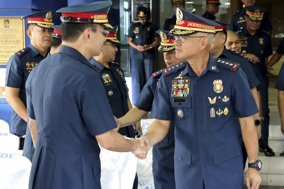 In this photo provided by Philippine National Police Public Information Office, Philippine National Police chief Gen. Oscar Albayalde, right, is congratulated by Police Maj.Gen. Guillermo Eleazar after the flag-raising ceremony at Camp Crame Monday, Oct. 14, 2019 in suburban Quezon city, northeast of Manila, Philippines. Albayalde resigned on Monday after he faced allegations in a Senate hearing that he intervened as a provincial police chief in 2013 to prevent his officers from being prosecuted for allegedly selling a huge quantity of illegal drugs they had seized. (Philippine National Police Via AP)