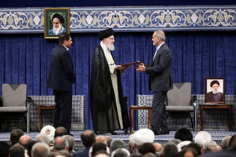 Iranian Supreme Leader Ayatollah Ali Khamenei (CL) hands his approval to newly elected President Masoud Pezeshkian during the ceremony to support the new president in Tehran. -/Iranian Presidency/dpa