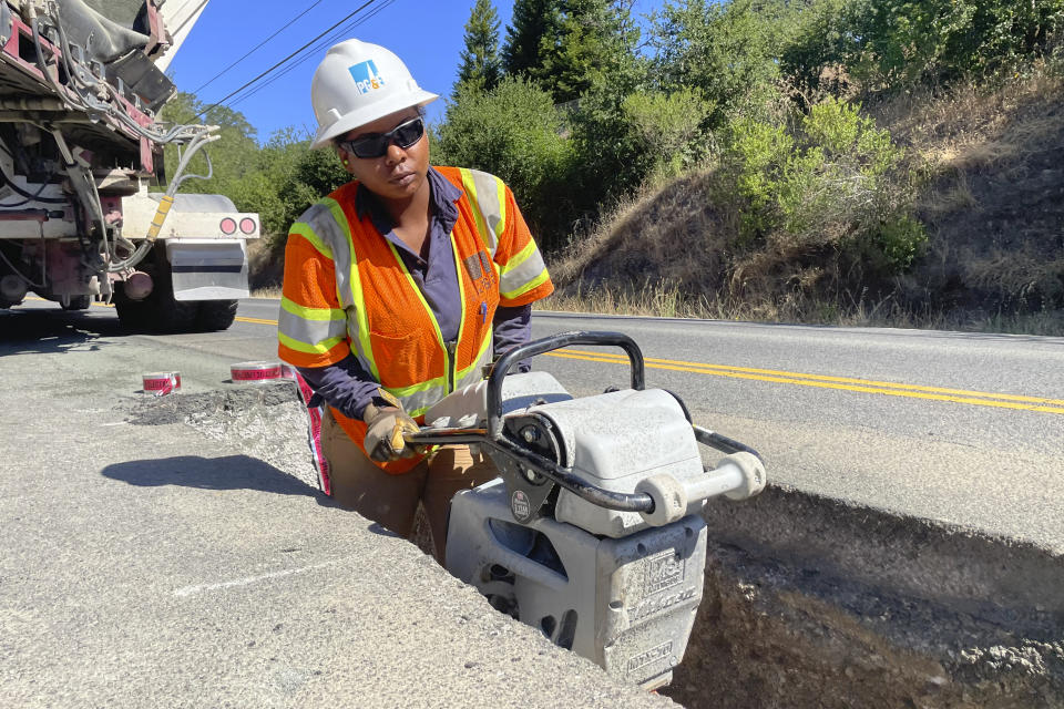 Jasmin Hardy, with a PG&E crew, works at installing underground power lines along Porter Creek Road in Sonoma County, Calif., site of the 2017 Tubbs Fire, on Monday, June 13, 2022. Pacific Gas & Electric Co. has started an ambitious project to bury underground thousands of miles of power lines in an effort to prevent igniting fires with its equipment and avoid shutting down power during hot and windy weather. (AP Photo/Haven Daley)