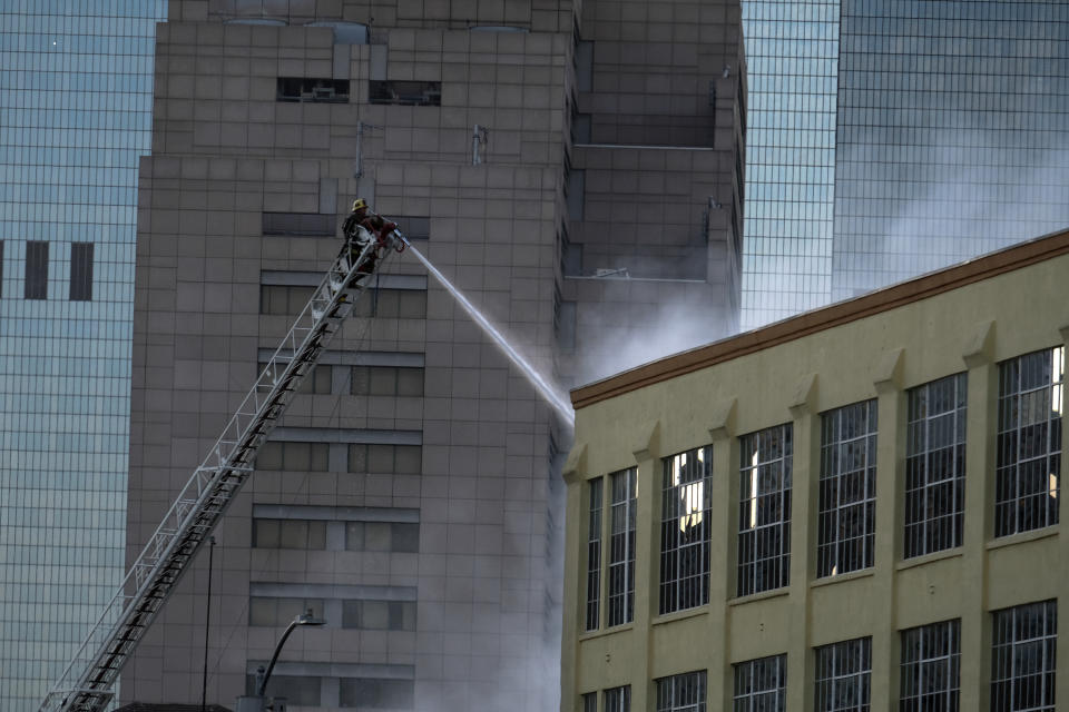 A Los Angeles Fire Department firefighter works the scene of a structure fire that injured multiple firefighters, according to a fire department spokesman, Saturday, May 16, 2020, in Los Angeles. (AP Photo/Ringo H.W. Chiu)