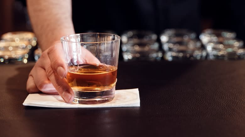 Bartender's hand serving neat bourbon