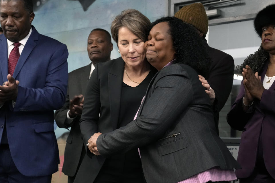 Massachusetts Gov. Maura Healey, center left, and Geralde Gabeau, founder and executive director of the Immigrant Family Services Institute, center right, embrace during a news conference, Wednesday, Jan. 31, 2024, at the Cass Recreational Complex, in the Roxbury neighborhood of Boston. The visit to the facility was held ahead of its planned opening as a temporary shelter site for families experiencing homelessness as the state continues to grapple with an influx of homeless migrants. (AP Photo/Steven Senne)