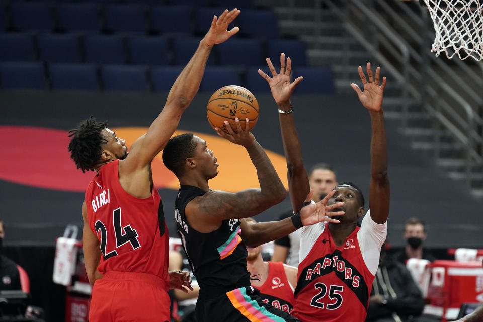 San Antonio Spurs guard Lonnie Walker IV (1) shoots between Toronto Raptors center Khem Birch (24) and forward Chris Boucher (25) during the second half of an NBA basketball game Wednesday, April 14, 2021, in Tampa, Fla. (AP Photo/Chris O'Meara)