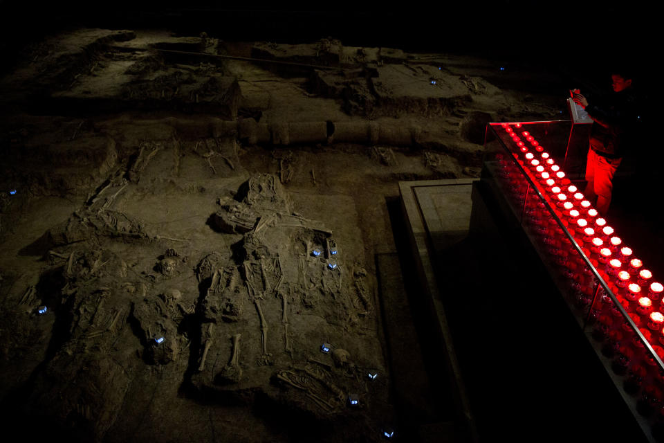 In this Feb. 11, 2014 photo, a visitor takes photos at a burial site at Nanjing Massacre Memorial Hall in Nanjing, in eastern China's Jiangsu province. The Tokyo shrine and the memorial hall in Nanjing, as Nanking is now called, are physical embodiments of divergent views of history that still strain China-Japan relations, 70 years after the war. (AP Photo/Alexander F. Yuan)