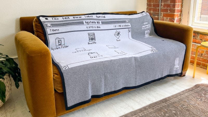 Throwboy's classic desktop knit cotton blanket draped over a couch in an apartment setting.