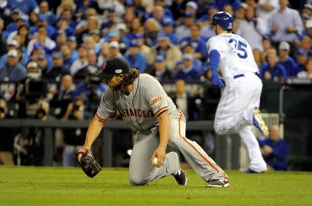 Oct 21, 2014; Kansas City, MO, USA; San Francisco Giants starting pitcher Madison Bumgarner (front) slides to field a ball hit by Kansas City Royals first baseman Eric Hosmer (35) in the 6th inning during game one of the 2014 World Series at Kauffman Stadium. John Rieger-USA TODAY Sports