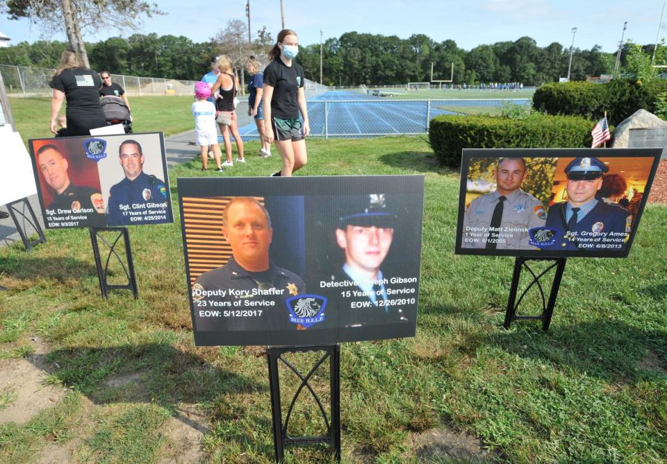 Photographs of police officers who died by suicide are displayed during the Law Enforcement Suicide Awareness Walk in Braintree, Saturday, Aug. 28, 2021.