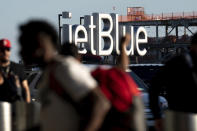 Travelers make their way near a JetBlue sign ahead of the Fourth of July holiday weekend at John F. Kennedy International Airport on Tuesday, June 28, 2022 in New York. (AP Photo/Julia Nikhinson)