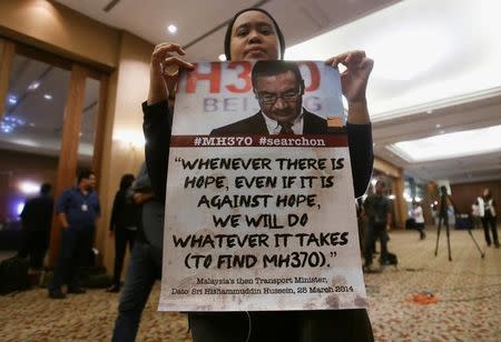 A family member of a passenger onboard the missing Malaysia Airlines flight MH370, shows a poster before the start of a news conference following a meeting with Joint Agency Coordination Centre (JACC) in Kuala Lumpur, Malaysia July 21, 2016. REUTERS/Lai Seng Sin