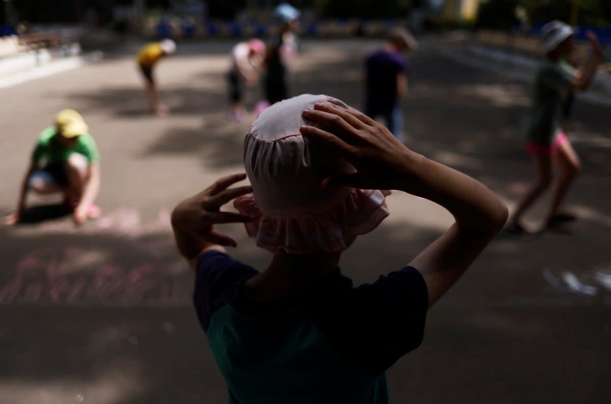 Tanya, 12, who is autistic and does not speak, watches other children draw with chalk in a play area at a facility for people with special needs in Odesa, Ukraine (Reuters)