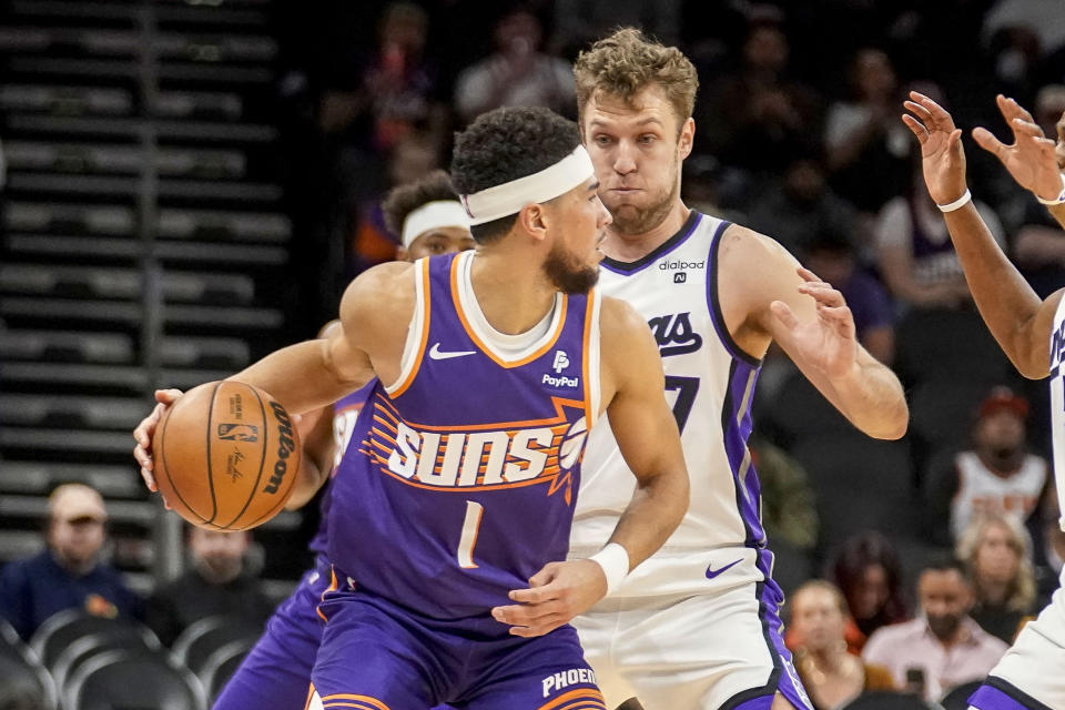 Sacramento Kings' Sasha Vezenkov (7) guards Phoenix Suns' Devin Booker (1) during the first half of an NBA basketball game Friday, Dec. 8, 2023 in Phoenix. (AP Photo/Darryl Webb)