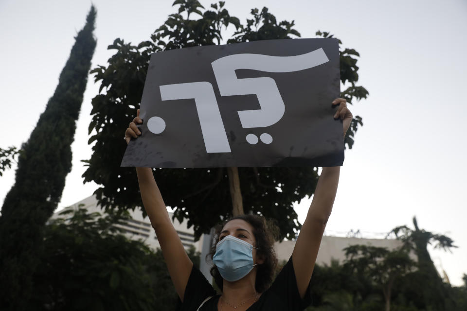 A woman holds a placard that reads, "go," during a protest against Prime Minister Benjamin Netanyahu in Tel Aviv, Israel, Thursday, Oct. 8, 2020 during a nationwide lockdown to curb the spread of the coronavirus. The Israeli government has extended an emergency provision that bars public gatherings, including widespread protests against Netanyahu, for an additional week. (AP Photo/Ariel Schalit)