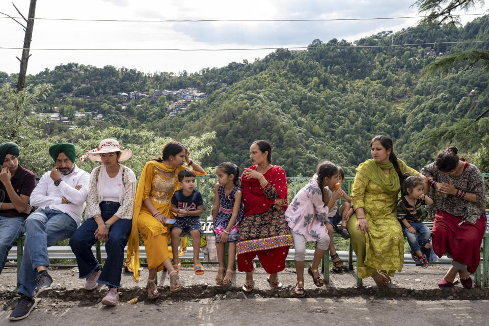 Tourists sit on public benches in Dharmsala, India, Friday, June 17, 2022. Summer travel is underway across the globe, but a full recovery from two years of coronavirus could last as long as the pandemic itself. (AP Photo/Ashwini Bhatia)