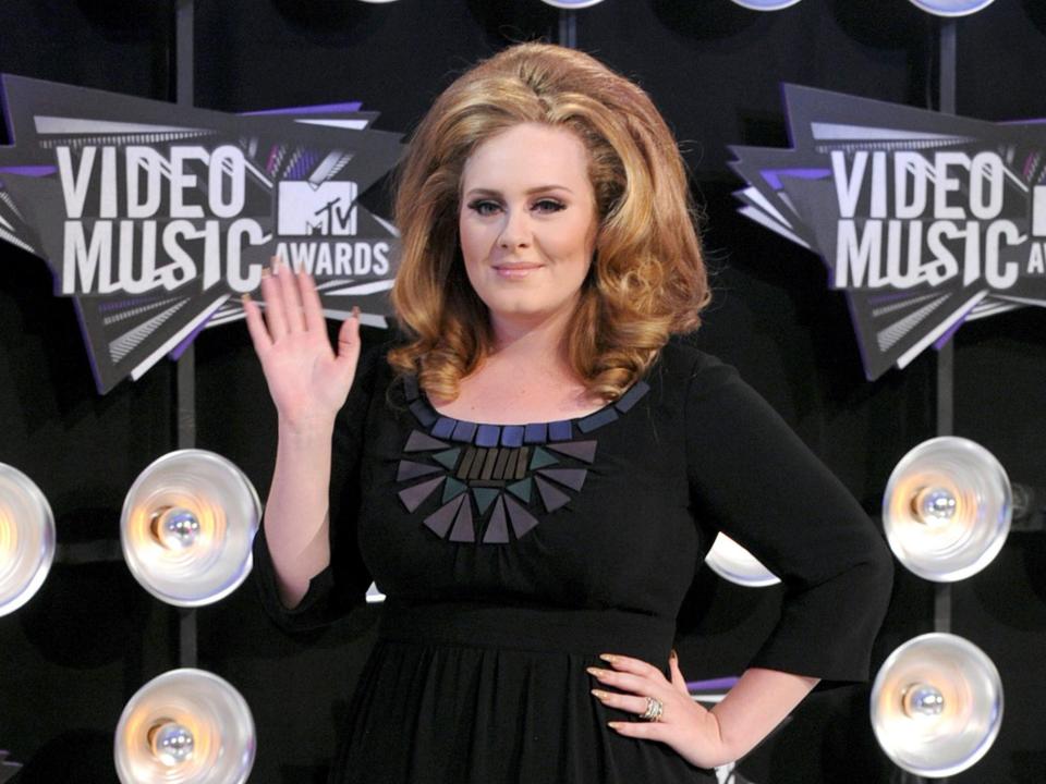 Adele waving in front of a VMAS backdrop.