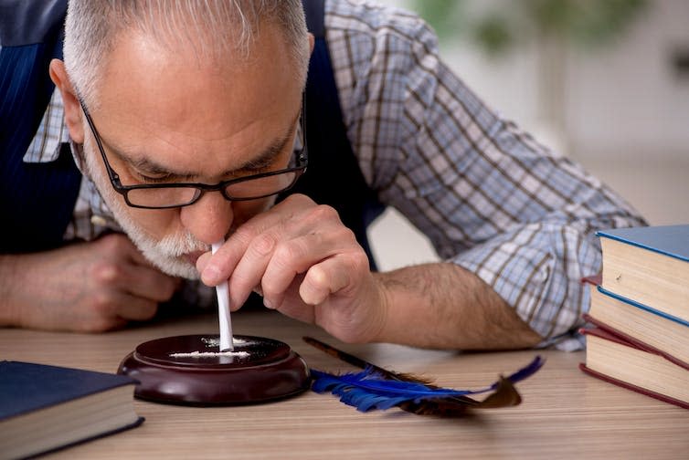 Older man snorting coke.