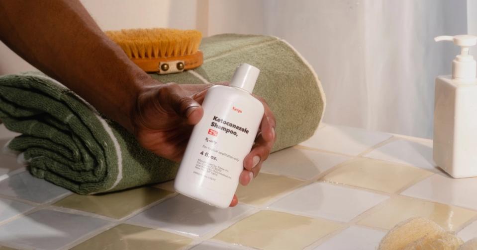 the keeps ketoconazole shampoo 2% being held by a man near the shower