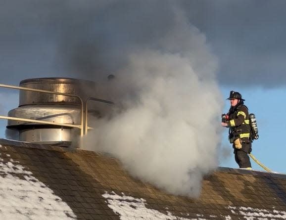 A firefighter battles a roof fire atop the Wells Sanitary District water treatment plant on Eldridge Road in Wells, Maine, in January of 2023.