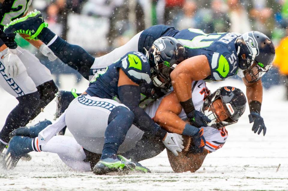 Seattle Seahawks middle linebacker Bobby Wagner (54) and outside linebacker Jordyn Brooks (56) team up to tackle Chicago Bears running back David Montgomery (32) during the first quarter of an NFL game on Sunday afternoon at Lumen Field in Seattle.