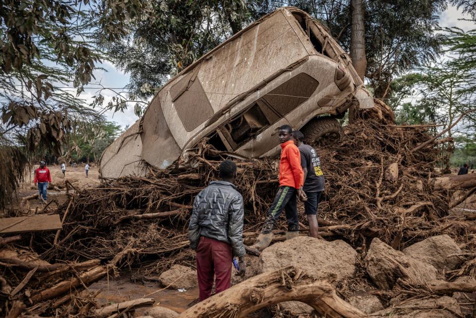 Young men inspect a wrecked car swept away by water in an area hit hard by torrential rains and flooding in Kamuchiri village, near Mai Mahiu, on April 29, 2024