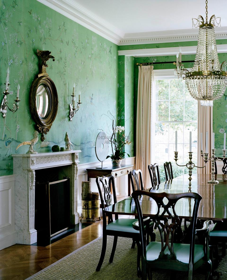 The dining room, sheathed in a hand-painted de Gournay wallpaper, features English Georgian table and chairs, a Louis XVI marble mantel, and a Federal eagle mirror in gilded wood.