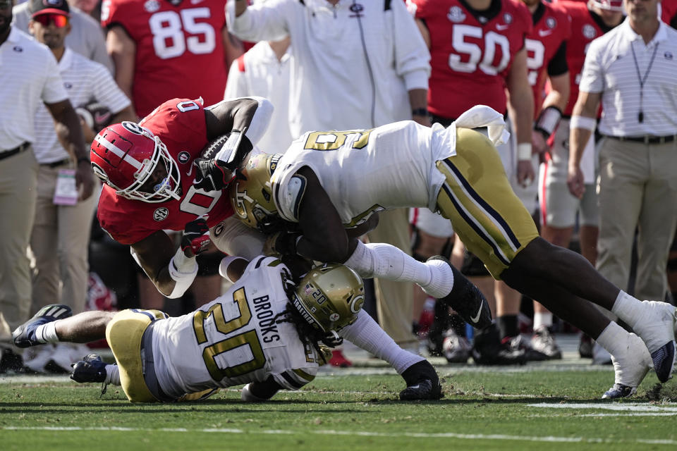 Georgia tight end Darnell Washington (0) is brought down down by Georgia Tech defenders LaMiles Brooks (20) and D'Quan Douse (99) during the first half of an NCAA college football game Saturday, Nov. 26, 2022 in Athens, Ga. (AP Photo/John Bazemore)