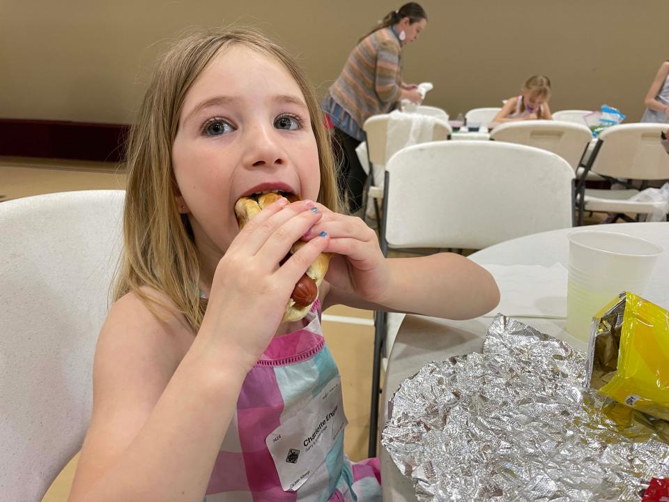 Charlotte Engle, 5, takes a big bite of her hotdog at the Easter Eggstravaganza at West Towne Christian Church, April 2, 2023.
