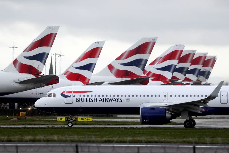 FILE PHOTO: BA plane taxis past tail fins of parked aircraft to runway near Terminal 5 at Heathrow Airport