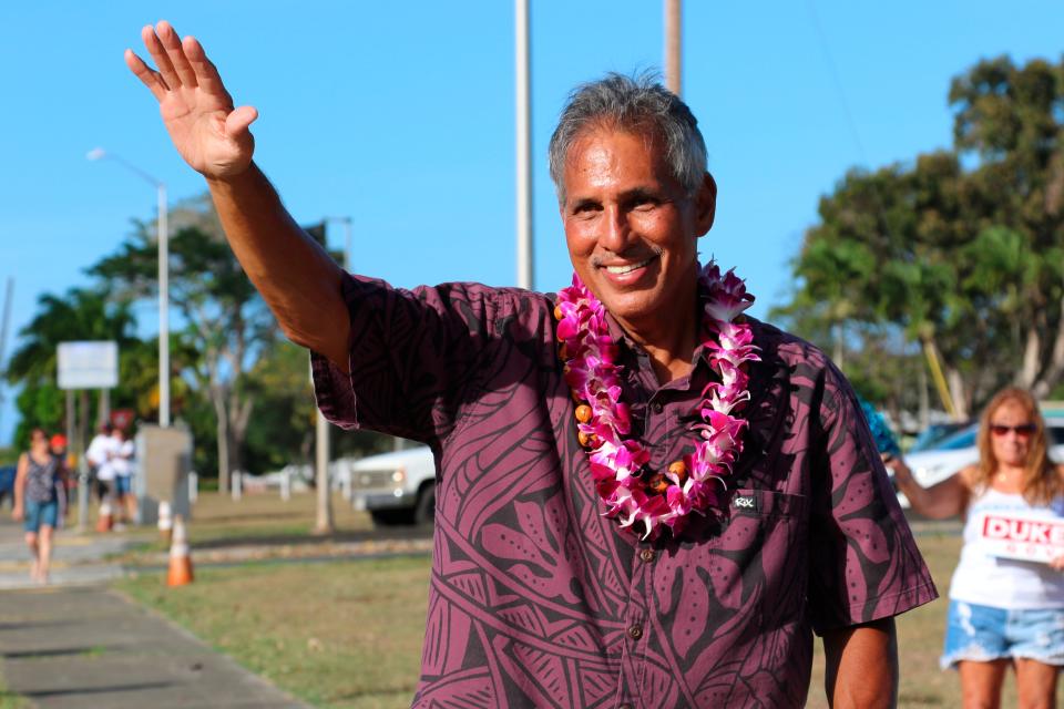 Former Hawaii Lt. Gov. James R. "Duke" Aiona waves at passing cars while campaigning in Kailua, Hawaii on Aug. 9, 2022. He's the Republican nominee for governor and has criticized Nomi's campaign contributions to his Democratic rival.