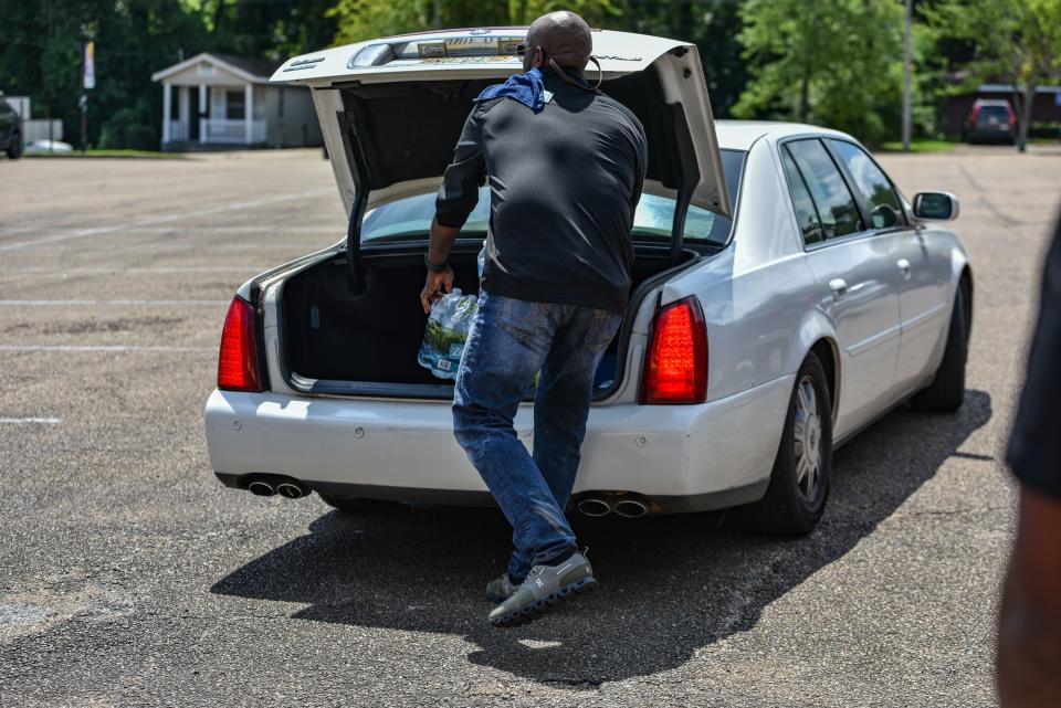 Morgan & Morgan Law Firm employees hand out water, baby wipes and other supplies to Jackson residents in need at Cade Chapel Missionary Baptist Church in Jackson, Miss., Wednesday, August 31, 2022.