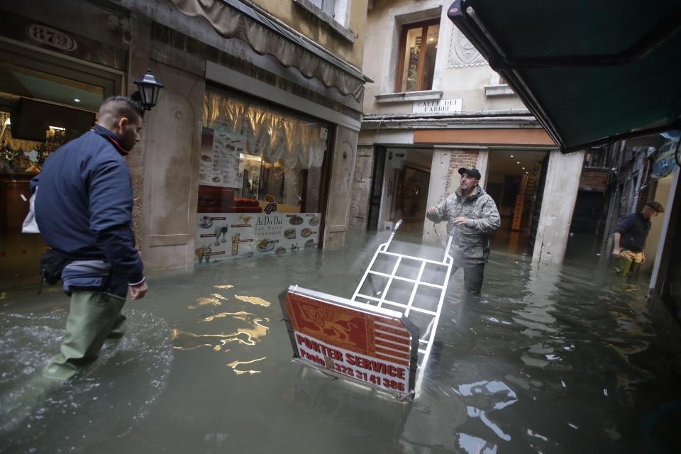 People make their way through the water in Venice, Italy, Friday, Nov. 15, 2019. Waters are rising in Venice where the tide is reaching exceptional levels just three days after the Italian lagoon city experienced its worst flooding in more than 50 years. (AP Photo/Luca Bruno)