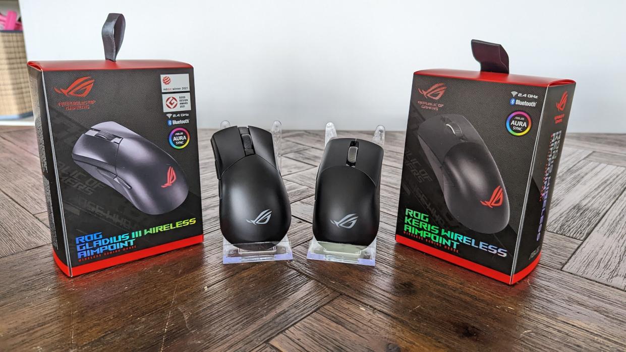 The ASUS ROG Gladius III Wireless Aimpoint and the ASUS ROG Keris Wireless Aimpoint on with its packaging on a wooden table.