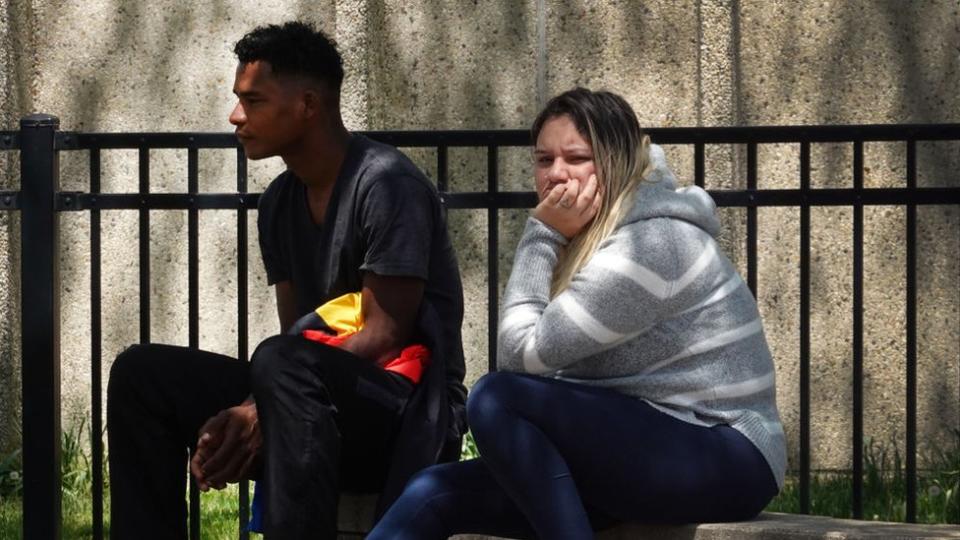 Familias migrantes de Venezuela observan cómo sus hijos juegan en un parque de Chicago, donde una casa de campo se ha convertido en un refugio para migrantes.