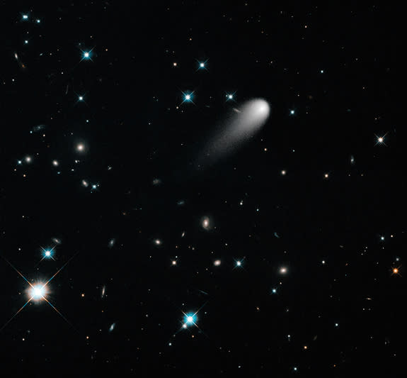 The sun-approaching Comet ISON floats against a seemingly infinite backdrop of numerous galaxies and a handful of foreground stars in this Hubble Space Telescope composite image, taken in April 2013.