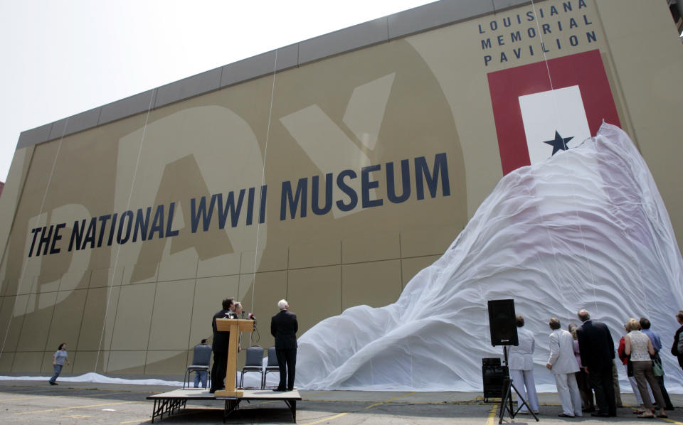 FILE- In this June 2, 2006 file photo, participants watch as the new name for the National D-Day Museum, The National World War II Museum, is unveiled in New Orleans. Before the COVID-19 pandemic hit, the National WWII Museum in New Orleans was planning on a 20th anniversary crowd of thousands. To avoid crowds during the coronavirus, the museum is selling museum tickets for specific times and is holding all D-Day commemorations, including the annual opening ceremony, online. (AP Photo/Bill Haber, File)