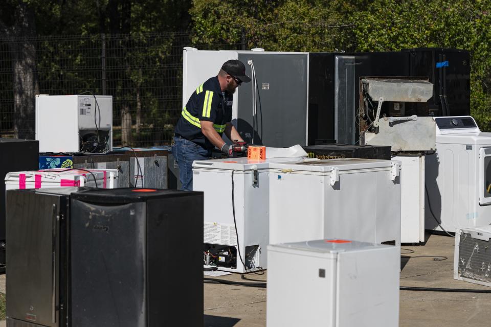 An operator attaches equipment to a used appliance at a customer recovery job site, Monday, Oct. 9, 2023, in Little Elm, Texas. The company A-Gas takes in shipments of refrigerators and tanks from around the country and beyond, drains them, then purifies and reclaims the chemicals, shipping out recycled product. This prevents the need for new chemical production. (AP Photo/Sam Hodde)