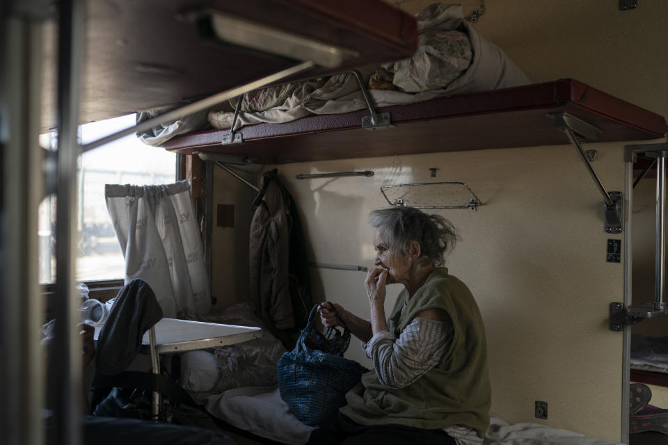 An elderly woman sits on a train at a train station in Pokrovsk, Ukraine, Monday, April 25, 2022, before departing to flee from the war in Severodonetsk and nearby towns. Russia unleashed a string of attacks against Ukrainian rail and fuel installations Monday, striking crucial infrastructure far from the front line of its eastern offensive. (AP Photo/Leo Correa)