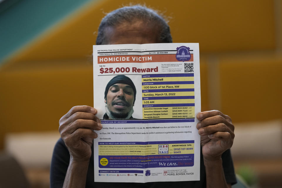 Natalia Mitchell, whose son Morris Mitchell was shot to death in March 2022, holds up the Metropolitan Police Department's homicide reward flyer in Washington, Monday, Oct. 30, 2023. (AP Photo/Susan Walsh)