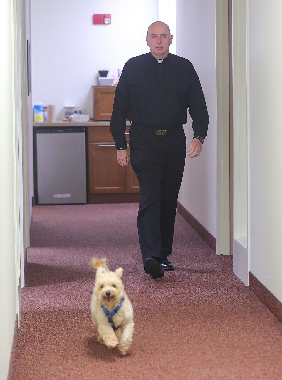 The Rev. Christopher Fronk walks with his dog Shipmate at Walsh Jesuit High School on Thursday. Fronk will become the new president of the Catholic high school at the start of July.