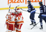 Calgary Flames' MacKenzie Weegar (52) celebrates his goal against the Winnipeg Jets with teammates during the first period of an NHL hockey game Thursday, April 4, 2024, in Winnipeg, Manitoba. (John Woods/The Canadian Press via AP)