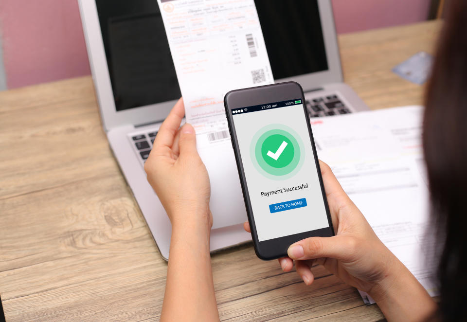 Hands holding mobile phone on blurred Electric bill as background