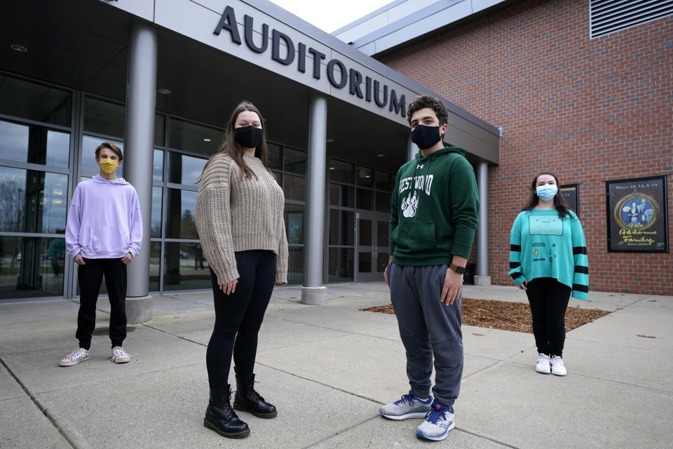 While wearing protective masks due to the COVID-19 outbreak, Lucy Vitali, who portrays Juliet, second from left, poses with Alex Mansour, who portrays Romeo, second from right, outside an auditorium after working on their virtual performance of Shakespeare's "Romeo and Juliet," at Westwood, Mass. High School, Monday, Nov. 16, 2020, in Westwood. The production, which would usually be presented onstage, shifted to a virtual audience due to the pandemic. With the duo are Ryan Kaplan, who portrays the friar, left, and Cassidy Hall, who portrays the nurse, right. (AP Photo/Charles Krupa)