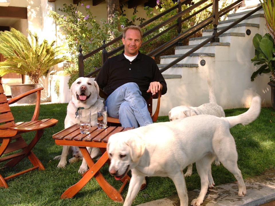 Kevin Costner sits with his dogs in the garden of one of his homes in 2002.