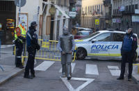 A street performers passes police officers controlling the access to the Rastro flea market in Madrid, Spain, Sunday, Nov. 22, 2020. Madrid's ancient and emblematic Rastro flea market reopened Sunday after a contentious eight-month closure because of the COVID-19 pandemic that has walloped the Spanish capital. (AP Photo/Paul White)