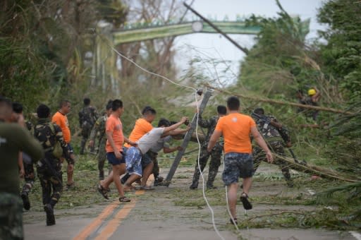 Rescue workers clear a road of debris and toppled electric posts caused by super Typhoon Mangkhut as they try to reach Baggao town