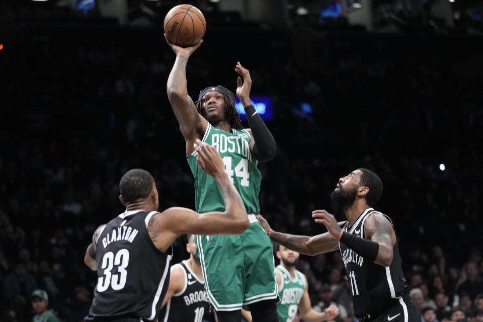 Boston Celtics center Robert Williams III (44) shoots as Brooklyn Nets center Nic Claxton (33) and guard Kyrie Irving (11) defend during the first half of an NBA basketball game Thursday, Jan. 12, 2023, in New York. (AP Photo/Mary Altaffer)