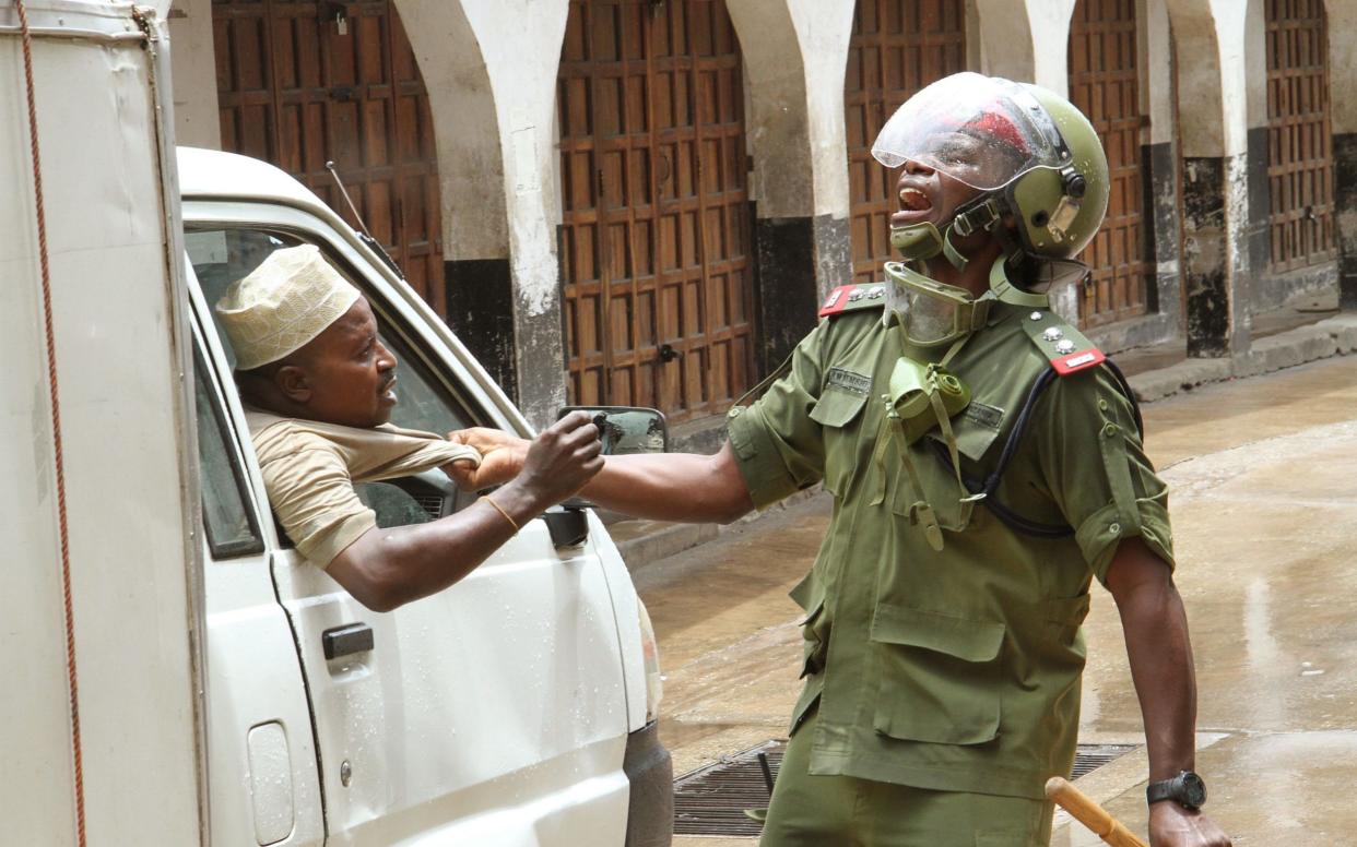 A police official attempts to pull a man from his van during ongoing security operations prior to Tanzania's general elections, in Stone Town, Zanzibar, Tanzania, 27 October 2020. - ANTHONY SIAME/EPA-EFE/Shutterstock /Shuttershock