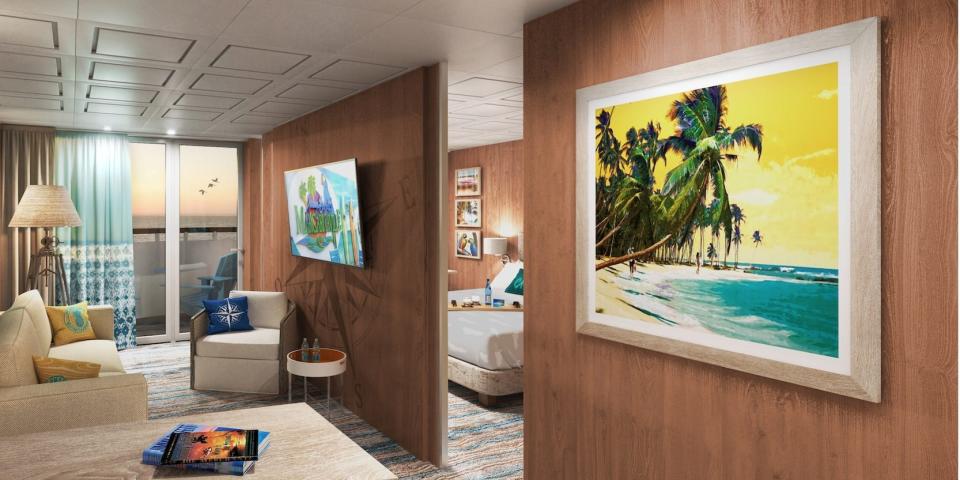 A suite aboard the Margaritaville Paradise with a couch, table, balcony, and bed in the corner