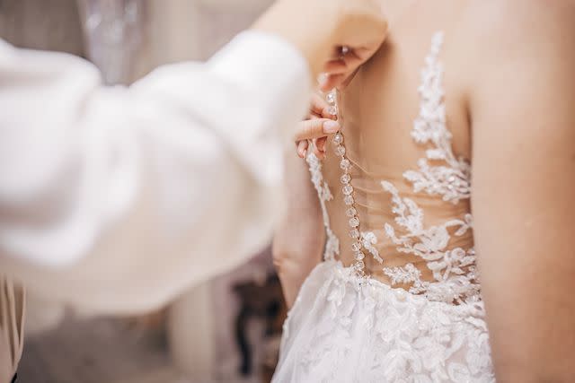 <p>Getty</p> Stock image of tailor taking measurements of a wedding dress while someone wears it